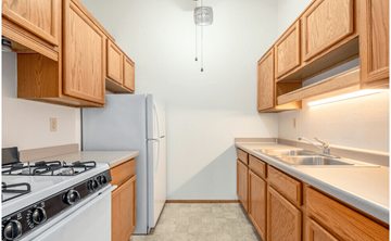 Greenfield apartment for rent - A kitchen with a white gas stove and wooden cabinets.