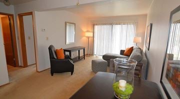 Milwaukee apartment for rent - A living room with a black chair and a glass vase with a white candle on a table.