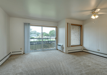 Milwaukee apartment for rent - A room with a carpeted floor, a ceiling fan, and a sliding glass door leading to a balcony.