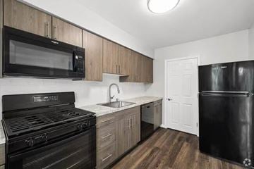 Maple Shade apartment for rent - A black stove and microwave in a kitchen with wooden cabinets.