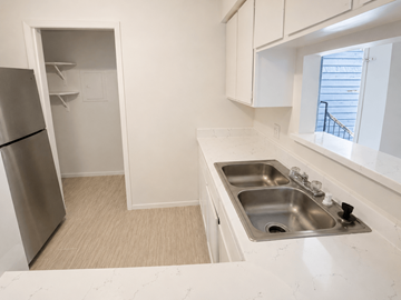 Houston apartment for rent - A kitchen with a stainless steel sink and a refrigerator with a door open.