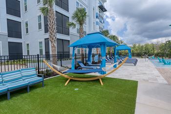 Poolside hammock area with artificial grass and cabanas