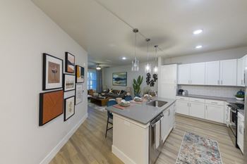 Open concept kitchen with white cabinetry and gallery wall