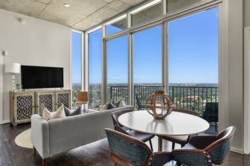 Houston apartment for rent - A living room with a grey couch, a round table and a television.