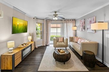 Palm Harbor apartment for rent - A living room with a brown floor and a painting of a sunrise on the wall.