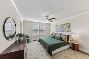 Fairburn townhouse for rent - A bedroom with a bed, a mirror, a ceiling fan, and a window.