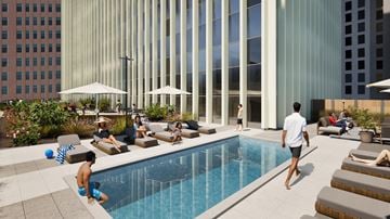 Des Moines apartment for rent - A man is walking towards a pool with people sitting around it.