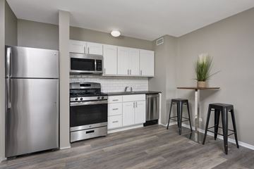 Chicago apartment for rent - A kitchen with a refrigerator, stove, and bar stools.