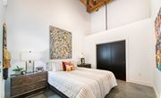 Greenville apartment for rent - A bedroom with a large bed and a painting on the wall. at Judson Mill Lofts and The Jenny & Westervelt in Greenville, SC