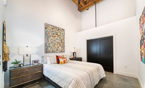 Greenville apartment for rent - A bedroom with a large bed and a painting on the wall. at Judson Mill Lofts and The Jenny & Westervelt in Greenville, SC