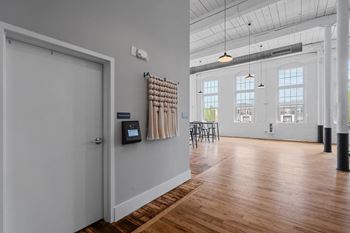 A large room with a door to a room with wood floors and white walls