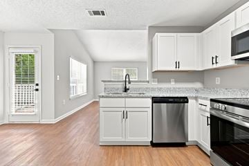 Creedmoor townhouse for rent - A kitchen with white cabinets and a wooden floor.