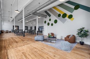 A living room with wood floors and white walls and chairs and couches