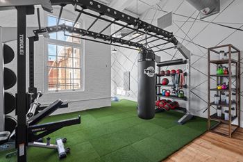 A gym with weights and a punching bag on a green rug