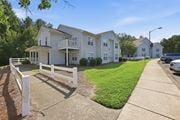 Creedmoor townhouse for rent - A white picket fence separates a driveway from a grassy area.