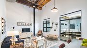 Greenville apartment for rent - A living room with a dark blue sofa, a wooden coffee table, and a TV on the wall at Judson Mill Lofts and The Jenny & Westervelt in Greenville, SC