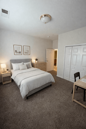 Elon townhouse for rent - A bedroom with a bed, nightstands, and a chair.