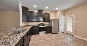 Hockley apartment for rent - A kitchen with black cabinets and a granite countertop.