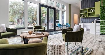Dallas apartment for rent - A living room with a green chair and a table with a vase on it.