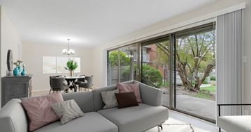 Overland Park apartment for rent - A living room with a grey couch and a dining table with chairs.