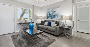 Tempe apartment for rent - A living room with a grey couch, a blue vase, and a painting on the wall.