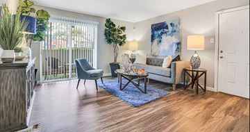 Houston apartment for rent - A living room with a grey couch, a blue rug, and a painting on the wall.