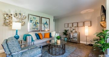 Arlington apartment for rent - A living room with a grey couch, a blue lamp, and a painting on the wall.