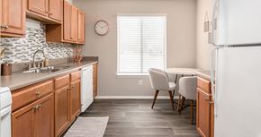 Richmond apartment for rent - a kitchen with wooden cabinets and a table with chairs