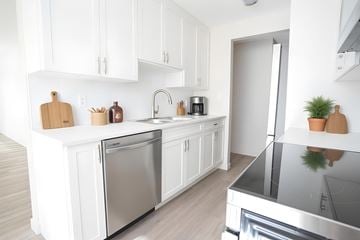 Kelowna apartment for rent - A modern kitchen with white cabinets and stainless steel appliances.