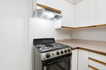 Kelowna townhouse for rent - A black and silver stove in a kitchen with white cabinets.