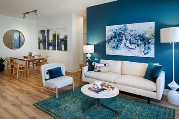 Houston apartment for rent - A living room with a white couch, a blue rug, and a painting on the wall.
