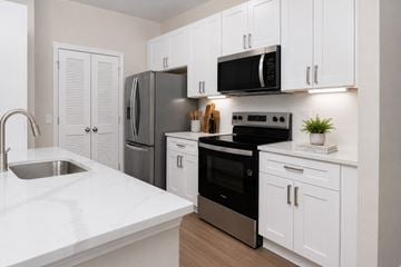 Orlando apartment for rent - A kitchen with white cabinets and a black fridge.
