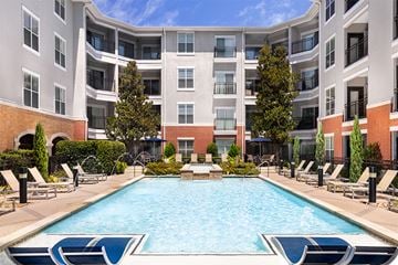Richardson apartment for rent - A large swimming pool in front of a multi-story apartment building.