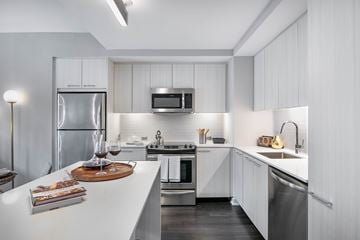 Reston apartment for rent - A modern kitchen with white cabinets and stainless steel appliances.