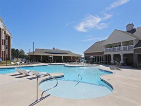 Benton apartment for rent - A large swimming pool with a slide and sun loungers in front of a building.