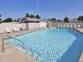 Russellville apartment for rent - A large swimming pool with a diving board and lounge chairs.