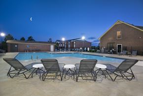 Broken Arrow apartment for rent - our apartments at night with a pool and chairs