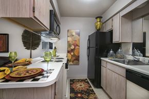 Broken Arrow apartment for rent - A kitchen with a black refrigerator and a table set for two.