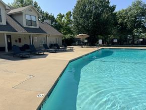 Russellville apartment for rent - A swimming pool in front of a house with a patio and lounge chairs.