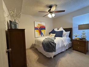 Russellville apartment for rent - A bedroom with a bed, a ceiling fan, and a painting on the wall.