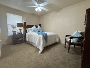 Little Rock apartment for rent - A bedroom with a bed, chair, and ceiling fan.