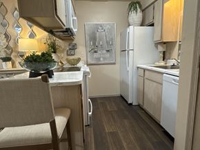 Little Rock apartment for rent - A kitchen with a white fridge, a table with a bowl on it and a chair.