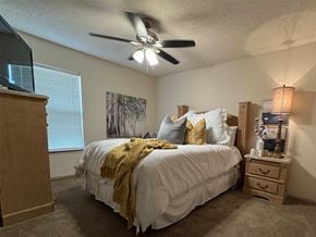 Texarkana apartment for rent - A bedroom with a bed, dresser, and ceiling fan.