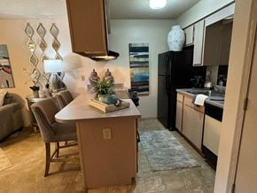 Texarkana apartment for rent - A kitchen with a black refrigerator and brown cabinets.