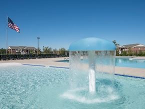 Norman apartment for rent - A water fountain in the middle of a pool with an American flag in the background.