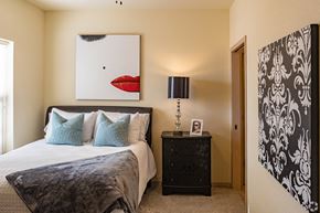 Norman apartment for rent - A bedroom with a large bed and a painting of a red mouth above it.