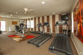 Owasso apartment for rent - a gym with treadmills and a tv on the wall