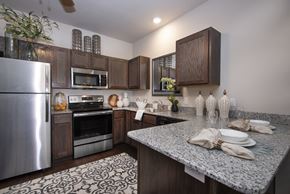 Benton apartment for rent - A kitchen with a refrigerator, microwave, oven, and a counter with plates and napkins on it.