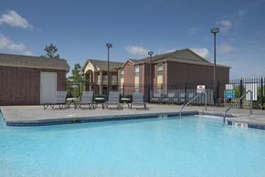 Broken Arrow apartment for rent - A swimming pool in front of a building with a fence around it.