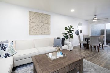Del Mar apartment for rent - A living room with a white couch, a wooden coffee table, and a dining table with chairs.